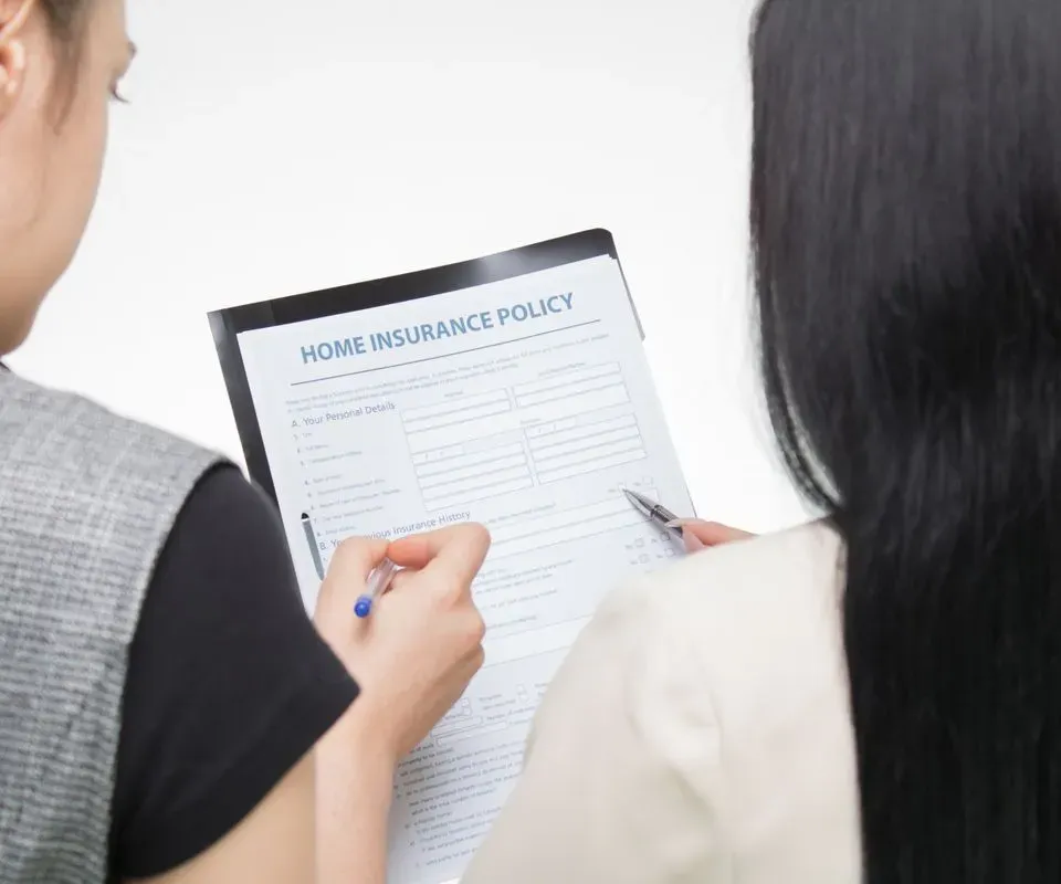 A person fills in a home insurance policy form with a pen
