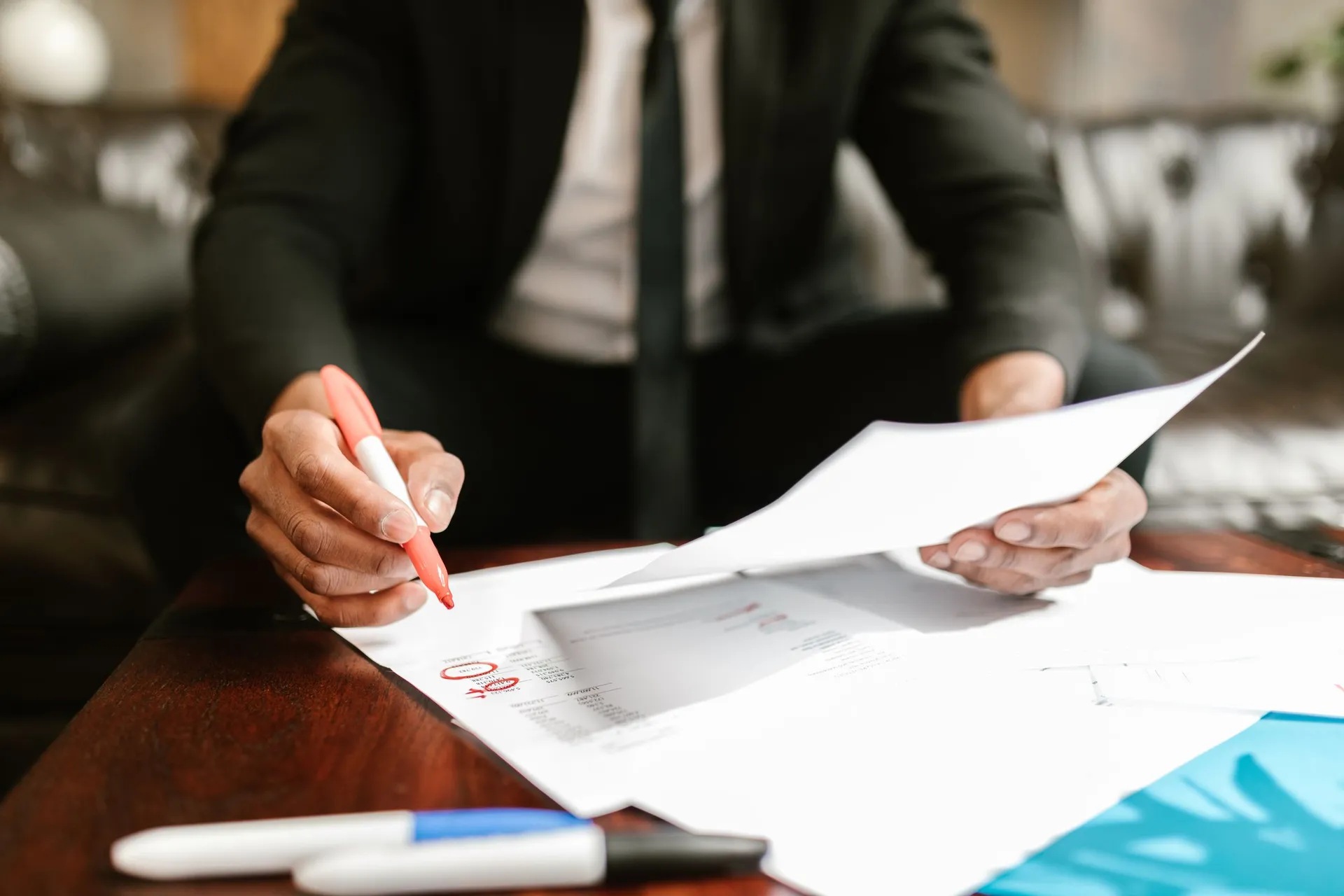 A reviewer in a suit marks figures on a printed page with a red pen