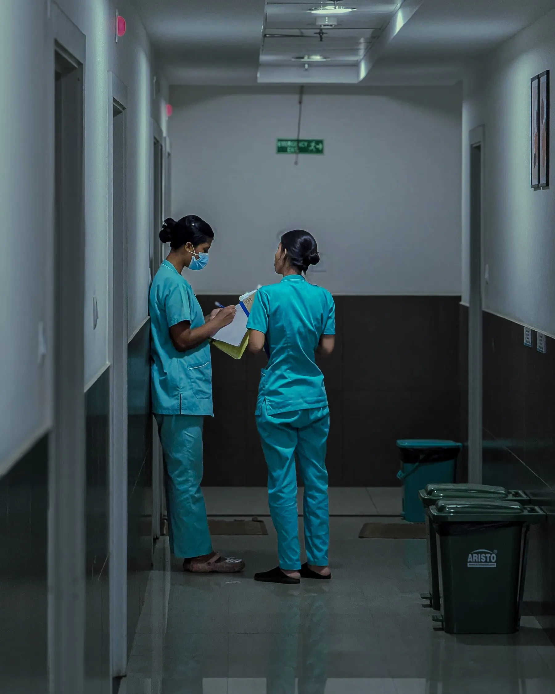 Two nurses in a hospital corridor reading a patient chart