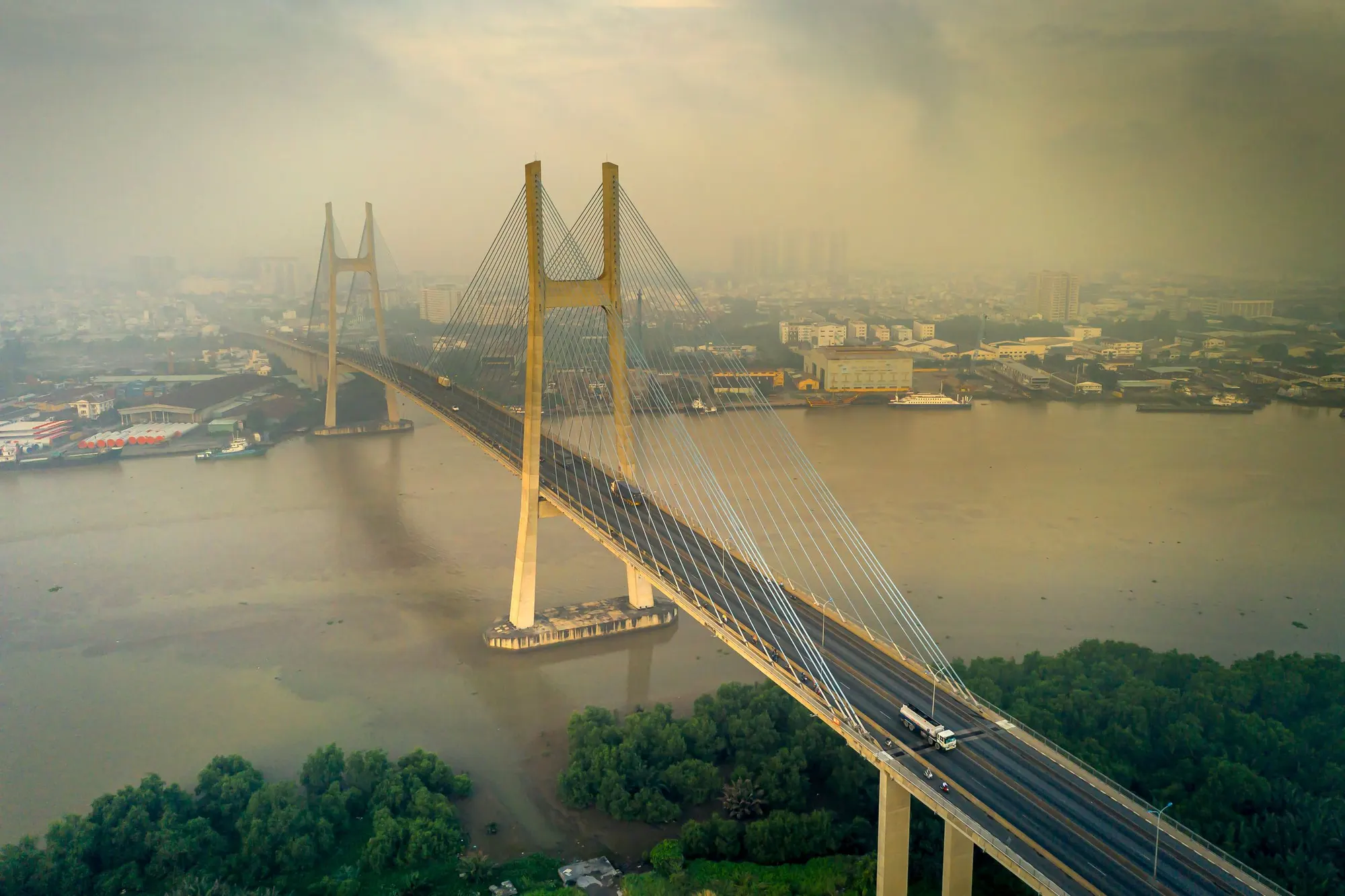 Aerial view of a cable-stayed bridge over a wide river in Ho Chi Minh City, in morning haze
