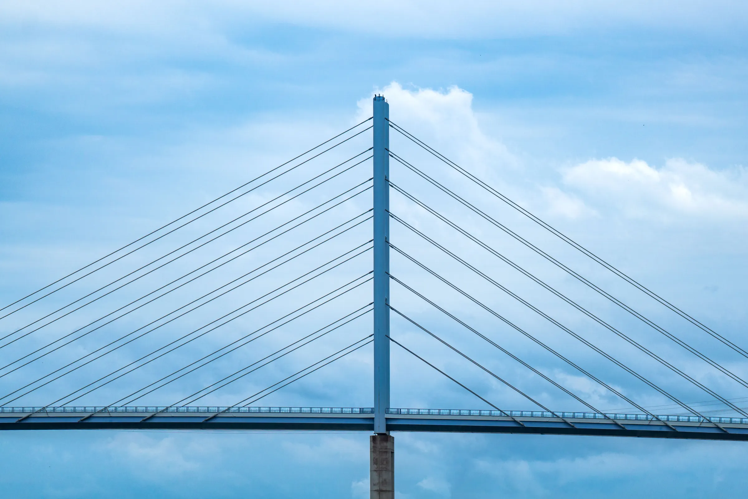 A cable-stayed bridge tower and its cables against a blue sky