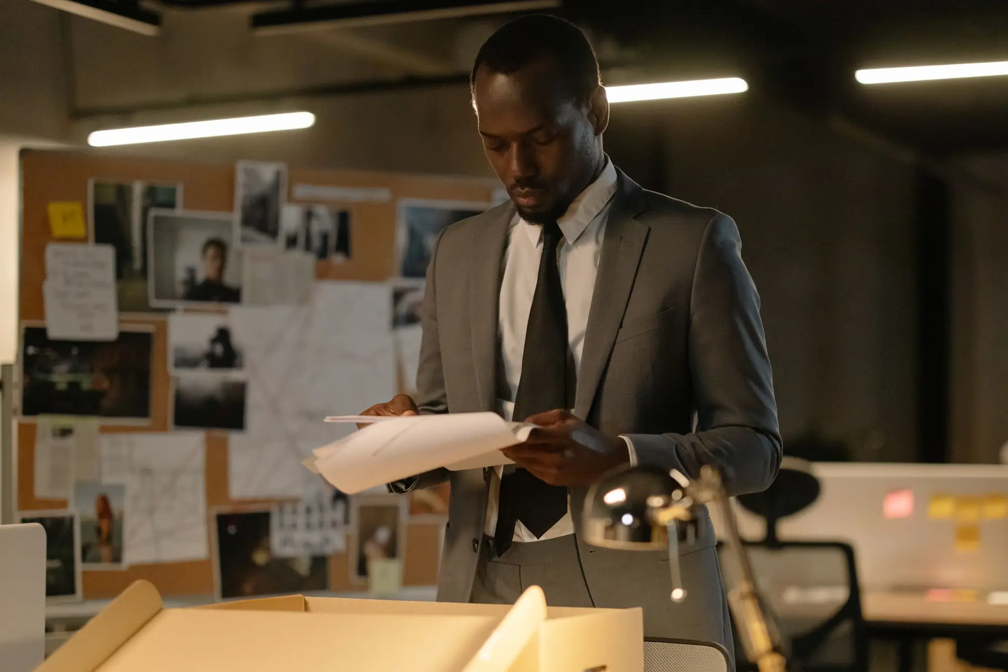 A lawyer in a grey suit reading a document in a dark office