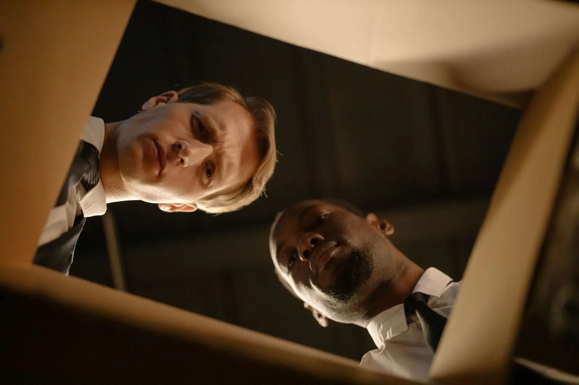 Two men looking down into an open file box