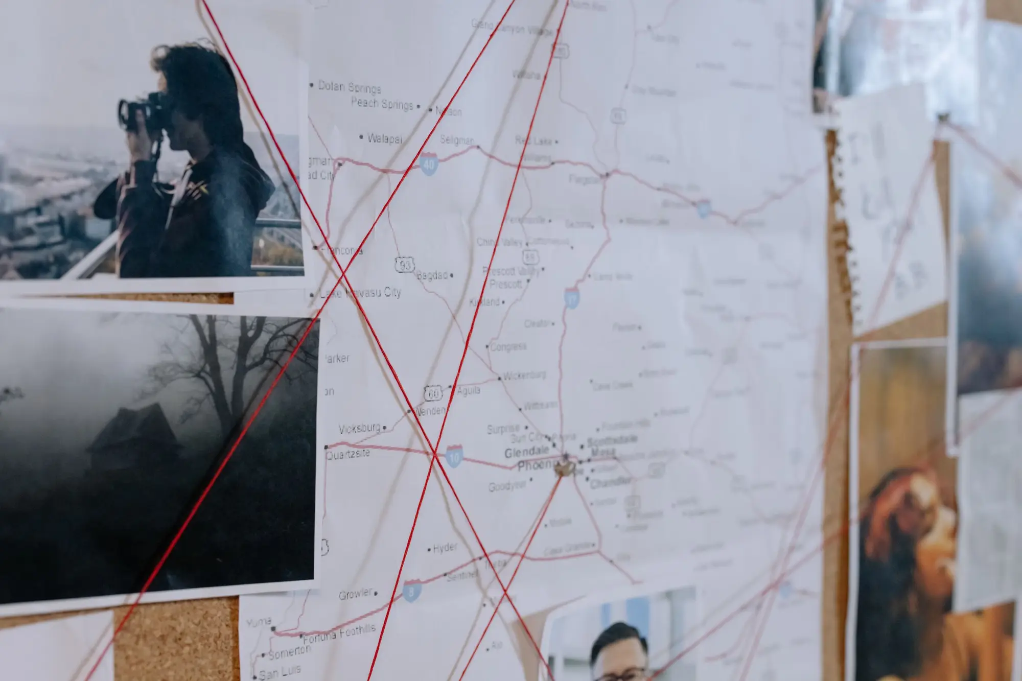 Red thread running across a map and the photos pinned around it