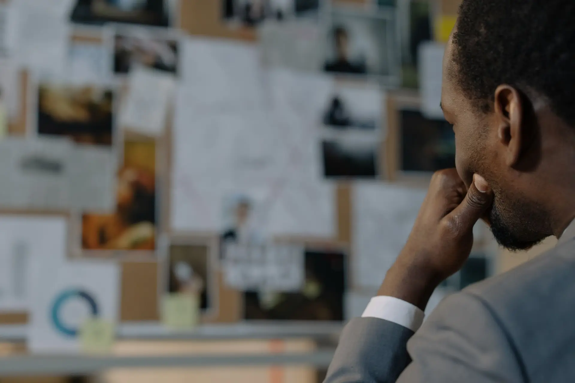 A lawyer thinking in front of a board of pinned documents and photos
