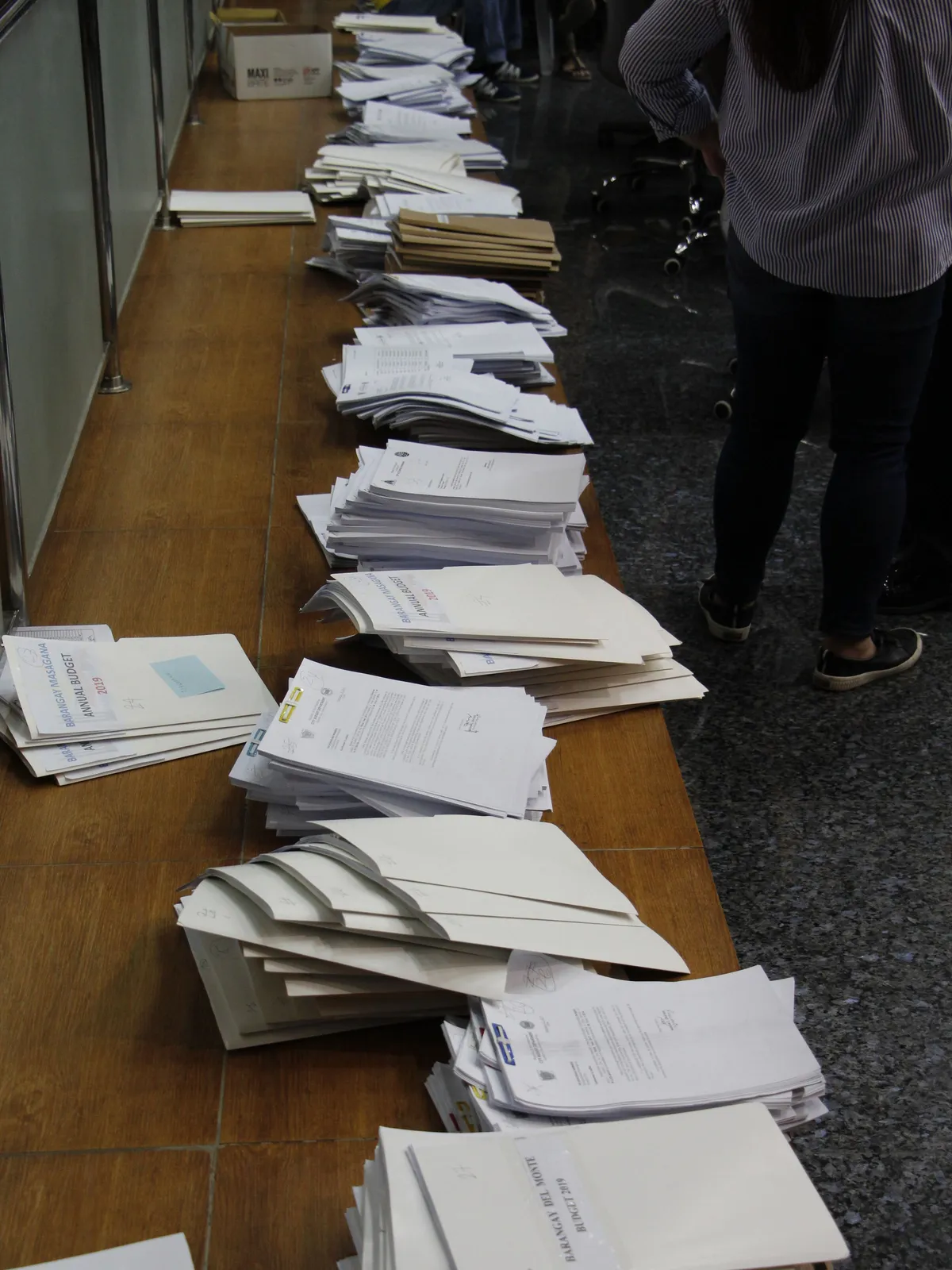 Piles of printed papers laid out along a long table